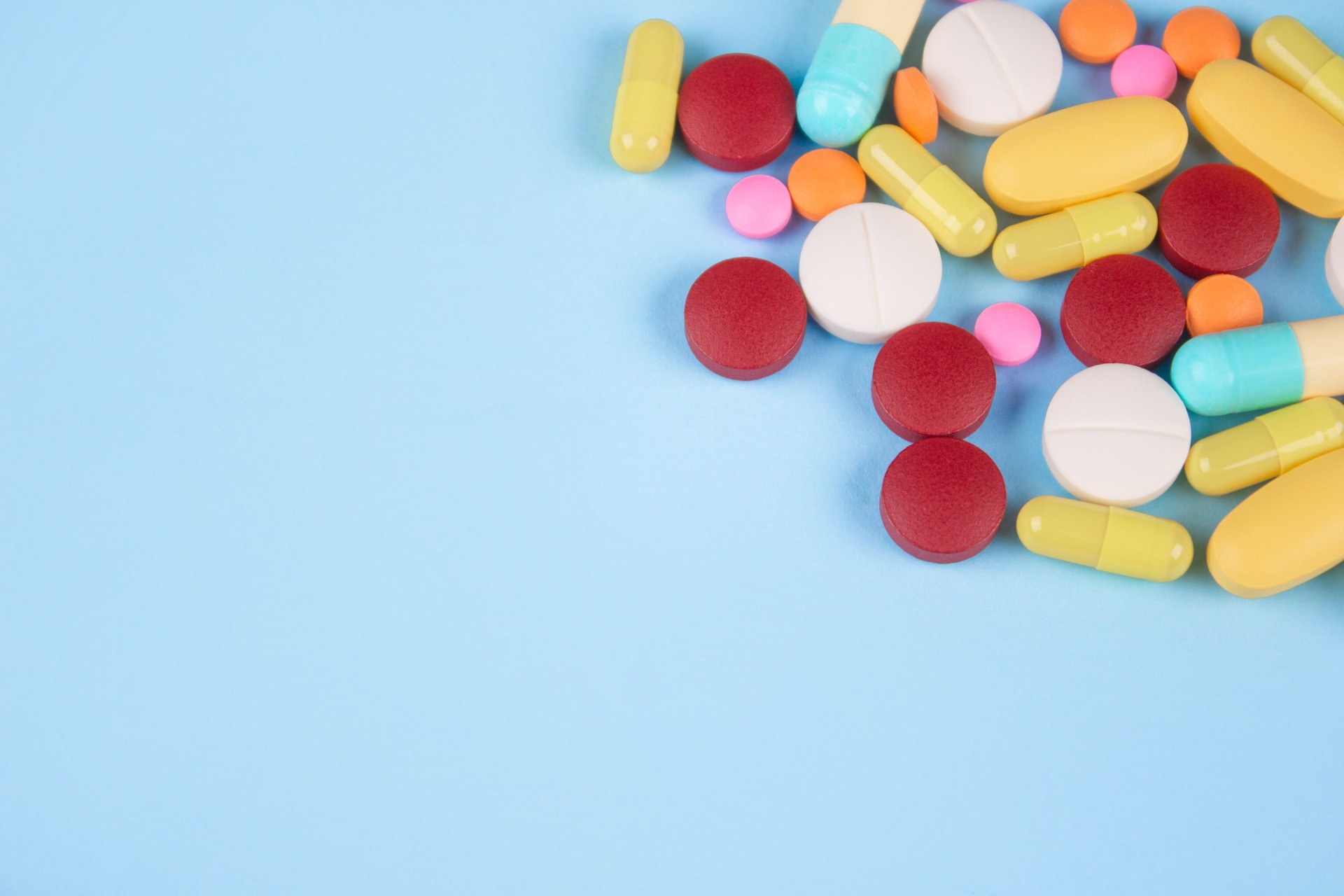 Assorted medicine pills, capsules and tablets on blue background with copy space. Immune system vitamins and supplemets. Selective focus